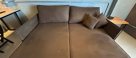 A modern, minimalist room with a large, brown sofa and a small wooden side table.