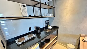 A modern kitchen with a black countertop, white appliances, and a built-in shelf above the sink. - SHB Magia de uma Vista Panorâmica (Santos)