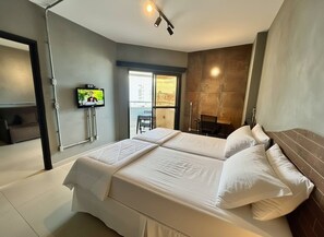A modern hotel room with a large bed, a television mounted on the wall, and a view of the city through the window. - SHB Magia de uma Vista Panorâmica (Santos)
