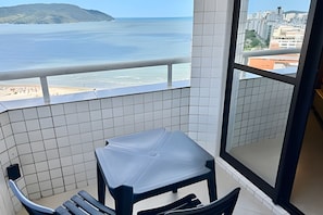 A balcony with a view of the beach and ocean, a small table, and a chair. - SHB Magia de uma Vista Panorâmica (Santos)