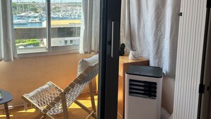 A balcony with a view of a marina, a hammock, a small table, and a portable heater.