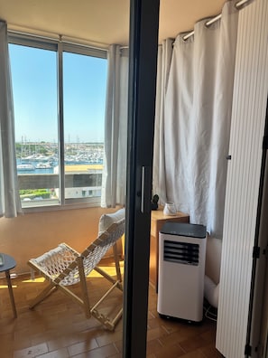 A balcony with a view of a marina, a hammock, a small table, and a portable heater.