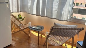 A balcony with two wicker chairs, a small table, and a potted plant.