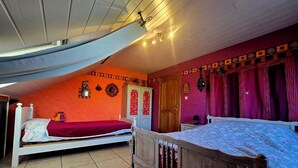 Un dormitorio con dos camas, un armario de madera, una puerta y un ventilador de techo.