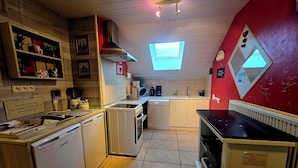 Cocina compacta con lavavajillas, microondas y una ventana pequeña.