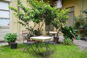 An outdoor seating area with a table and chairs, surrounded by potted plants and a tree. - Turin City Centre | Mazzini 39 House (Torino)