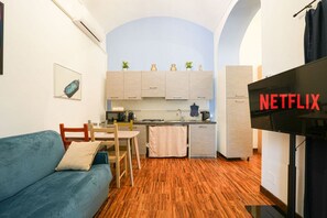 A compact living space with a kitchenette, a sofa, a dining area, and a TV screen displaying 'NETFLIX'. - Turin City Centre | Mazzini 39 House (Torino)