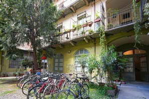 A courtyard with bicycles parked, a tree, and potted plants. - Turin City Centre | Mazzini 39 House (Torino)
