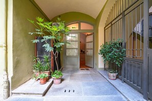 A covered entrance with potted plants, a tiled floor, and a door leading inside. - Turin City Centre | Mazzini 39 House (Torino)