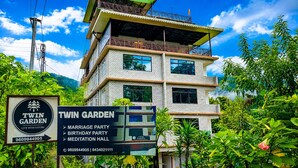 A multi-story building with a sign for Twin Garden, indicating it hosts events like marriage and birthday parties and has a meditation hall. - Twin Garden by TAPSOM (Gangtok)
