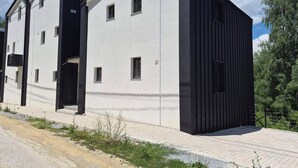 Ein modernes, zweistöckiges Gebäude mit flachem Dach, großen Fenstern und schwarzer Fassade.