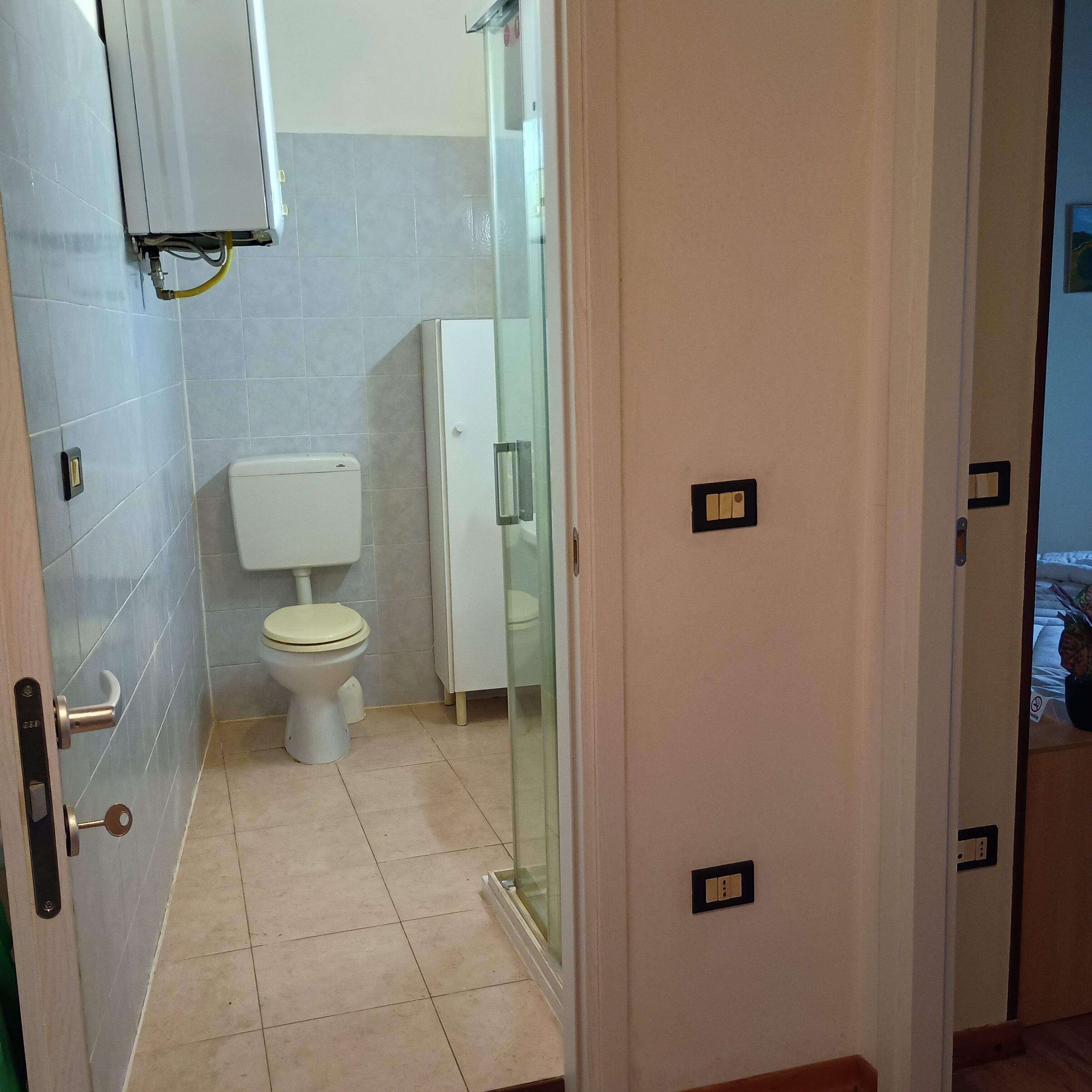 Un baño con inodoro, cabina de ducha de vidrio y un mueble blanco.