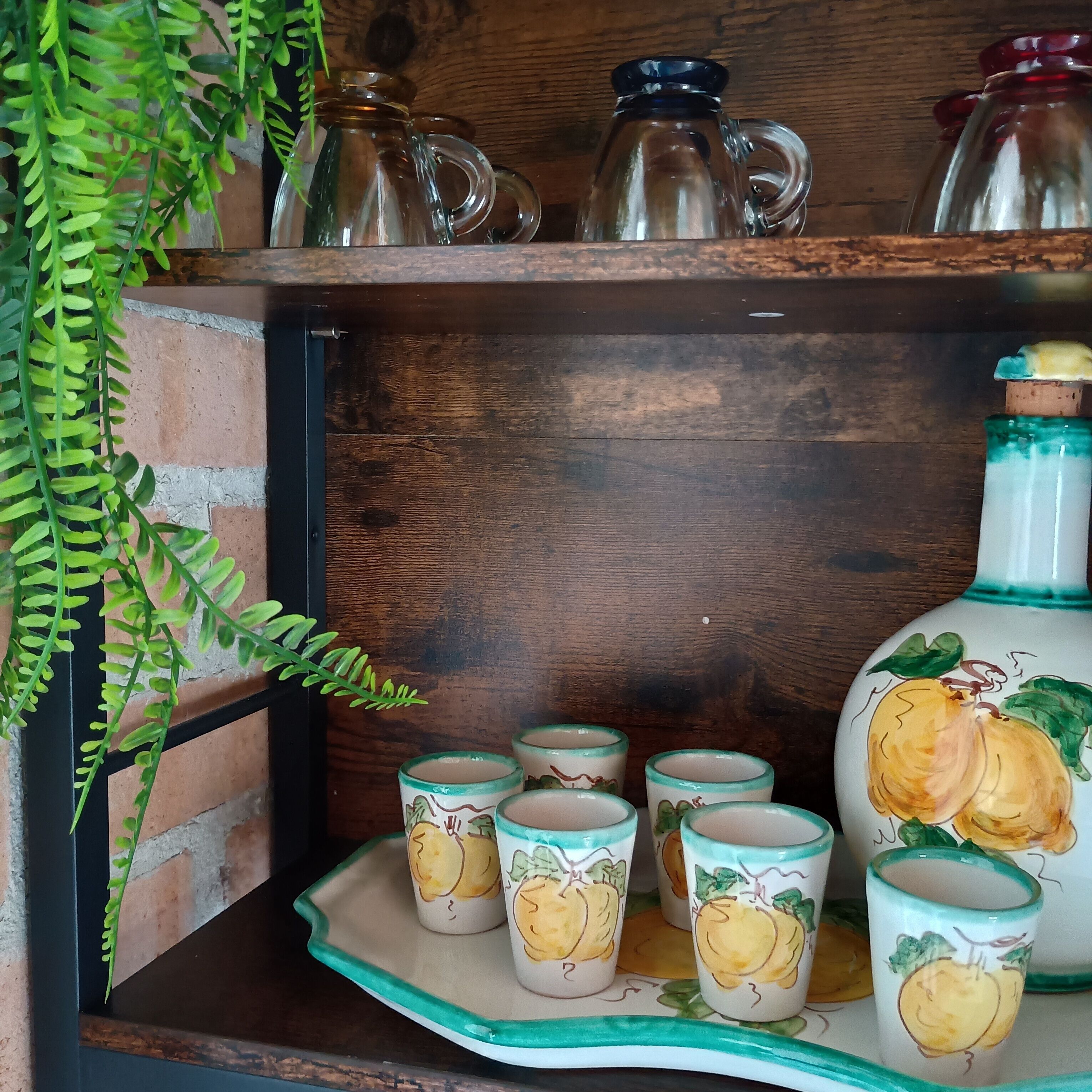 Une étagère avec des verres et des tasses en céramique décorées de motifs de fruits.
