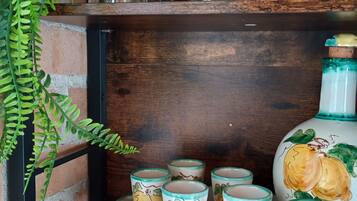 Une étagère avec des verres et des tasses en céramique décorées de motifs de fruits.
