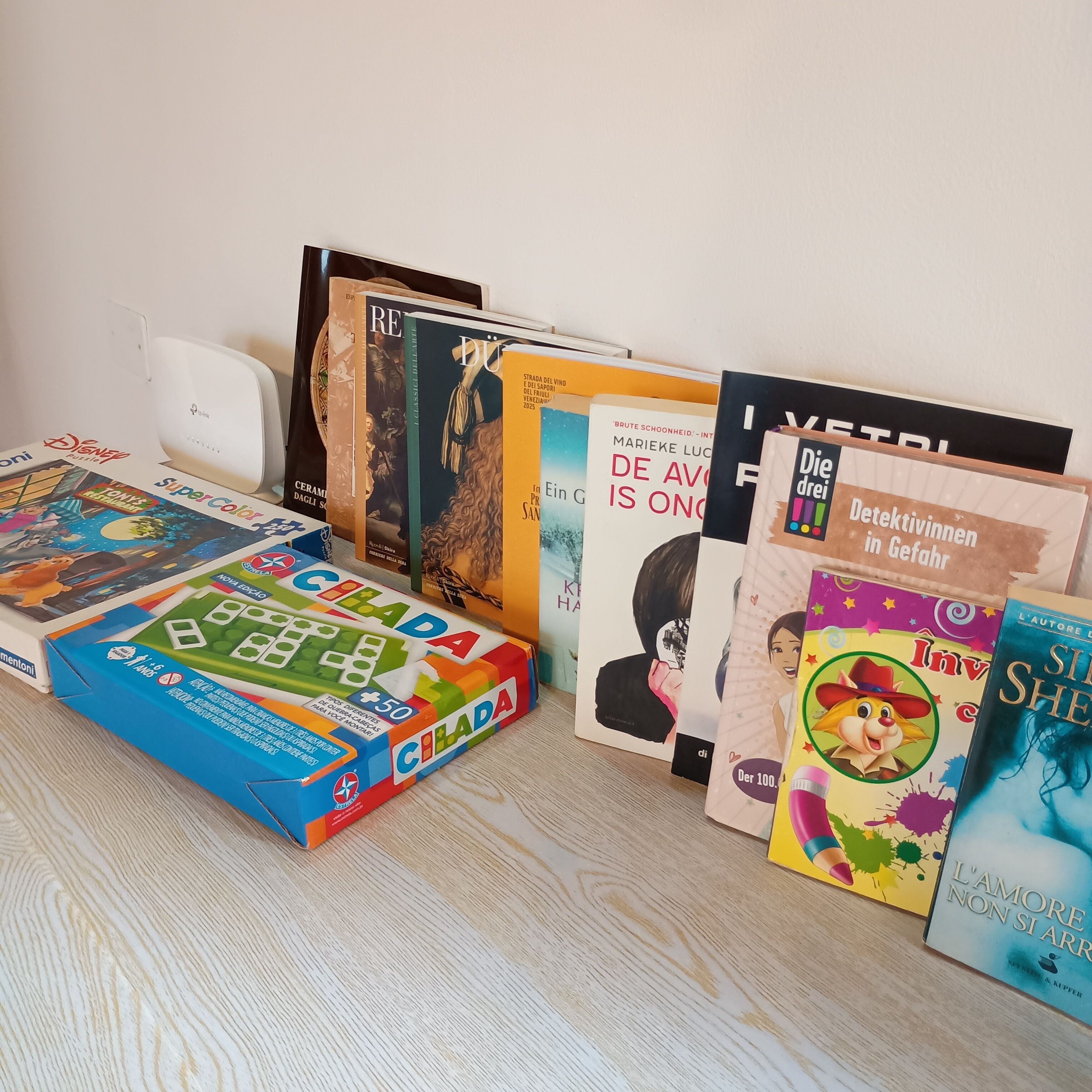 A collection of books and a puzzle on a wooden surface.