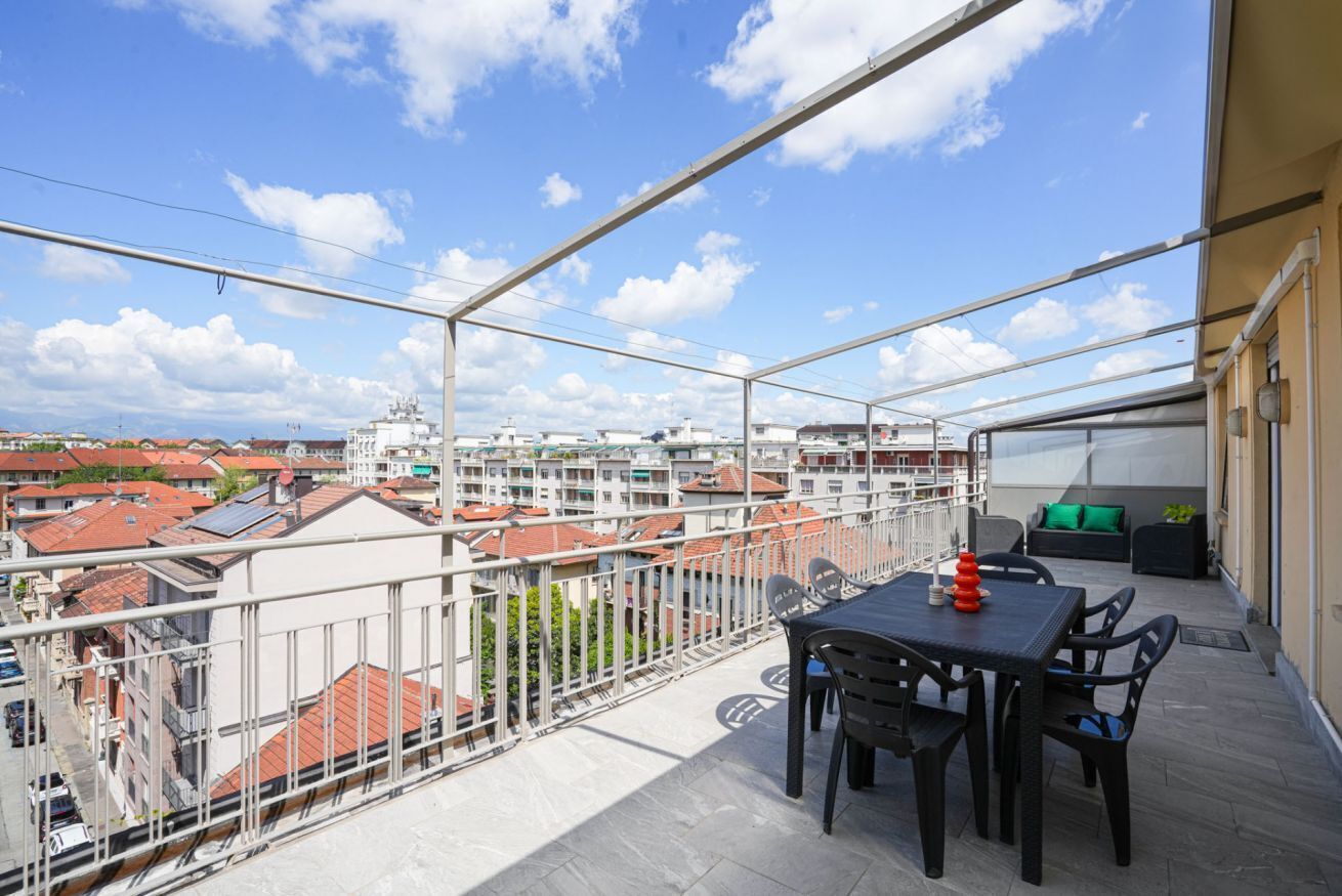 Un balcone con tavolo e sedie, una ringhiera e vista sui palazzi.
