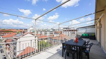 Un balcone con tavolo e sedie, una ringhiera e vista sui palazzi.
