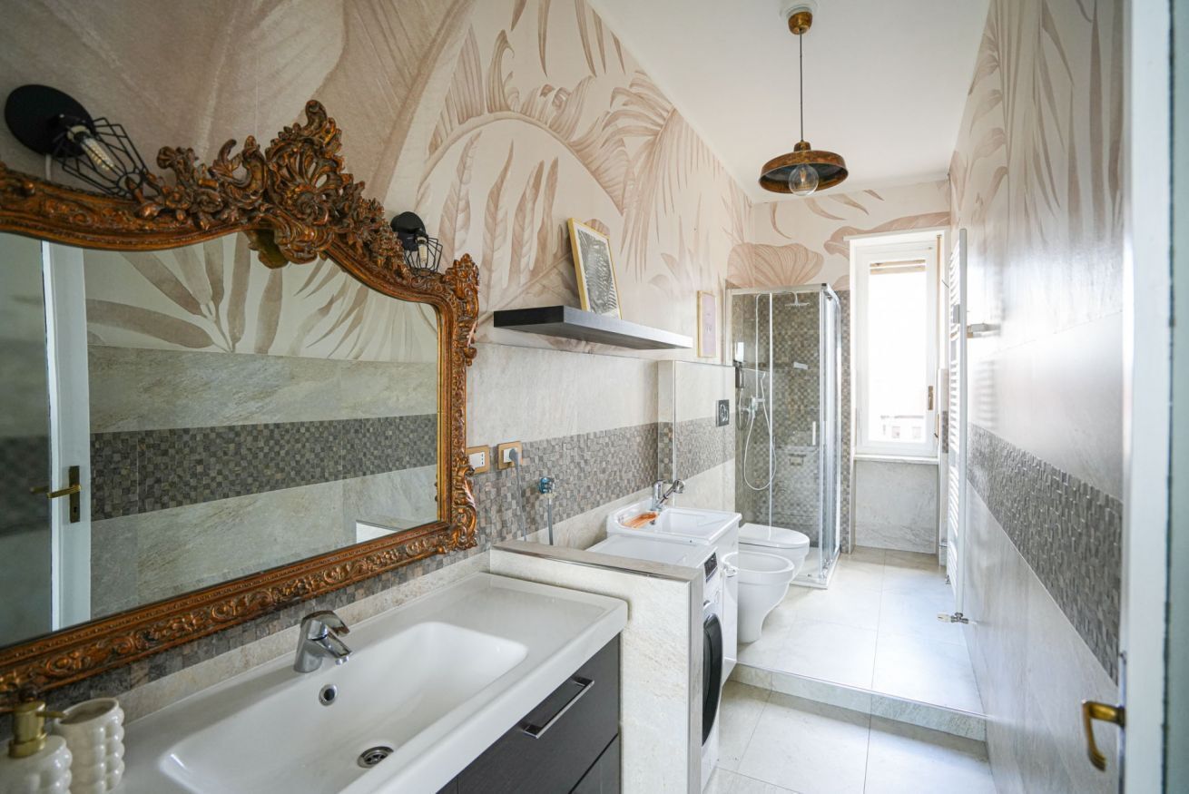 Ein Badezimmer mit einem großen, verzierten Spiegel, einem Waschbecken, einer Toilette und einer Duschkabine.