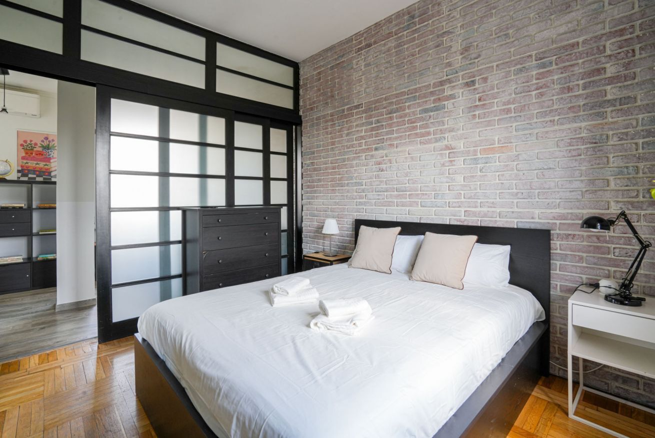 Ein modernes Schlafzimmer mit einem großen Bett, einer Ziegelwand und einem Holzboden.