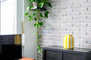 Ein Zimmer mit Backsteinwand, einer Pflanze und einem Schrank mit einer Vase.