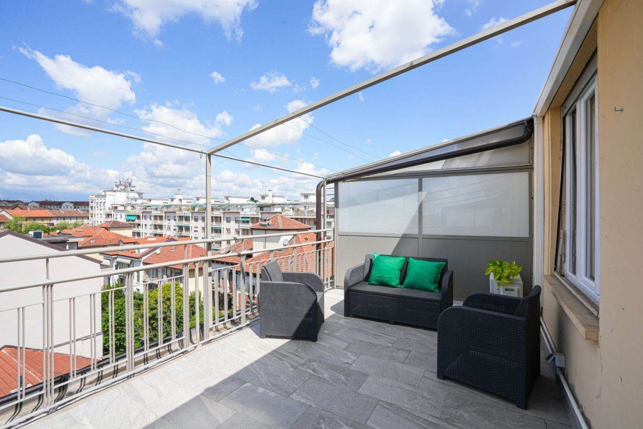 Un balcone con mobili da esterno, vista su edifici e cielo sereno.
