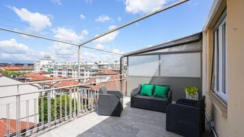 Un balcone con mobili da esterno, vista su edifici e cielo sereno.