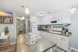 A modern kitchen with white cabinetry, a granite countertop, and a built-in microwave. - Resting Beach Face! - Ocean Lakes 3BR w/ Golf Cart Near the Beach! (Myrtle Beach)
