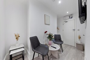 A modern room with a marble table, two chairs, a vase with dried flowers, and a painting on the wall. - Harlesden Haven Studio (London)