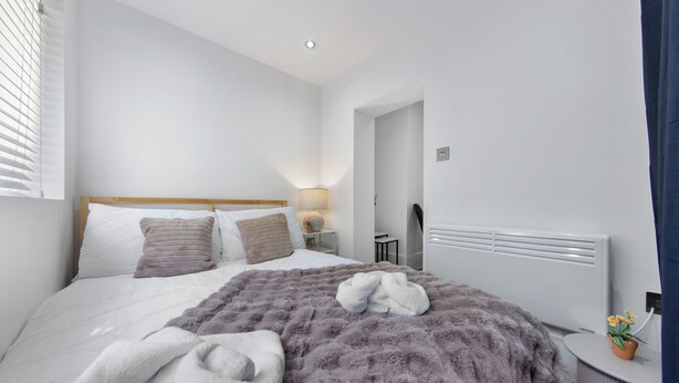 Une chambre d’hôtel avec un lit, une table de chevet, une lampe et un radiateur.