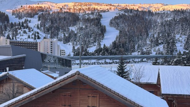 A wooden cabin with a sloped roof, surrounded by snow-covered trees and a mountain in the background. - Renovated Apartment in Super Dévoluy with Heated Pool and Sauna (Dévoluy)
