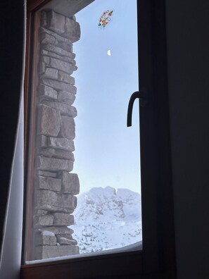 A stone wall window with a view of a snowy landscape and a crescent moon. - Renovated Apartment in Super Dévoluy with Heated Pool and Sauna (Dévoluy)