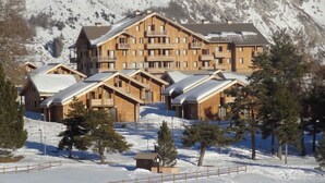 A multi-story lodge with a symmetrical design, featuring balconies and a snow-covered landscape. - Renovated Apartment in Super Dévoluy with Heated Pool and Sauna (Dévoluy)