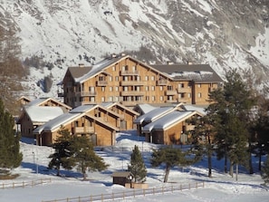 A multi-story lodge with a symmetrical design, featuring balconies and a snow-covered landscape. - Renovated Apartment in Super Dévoluy with Heated Pool and Sauna (Dévoluy)