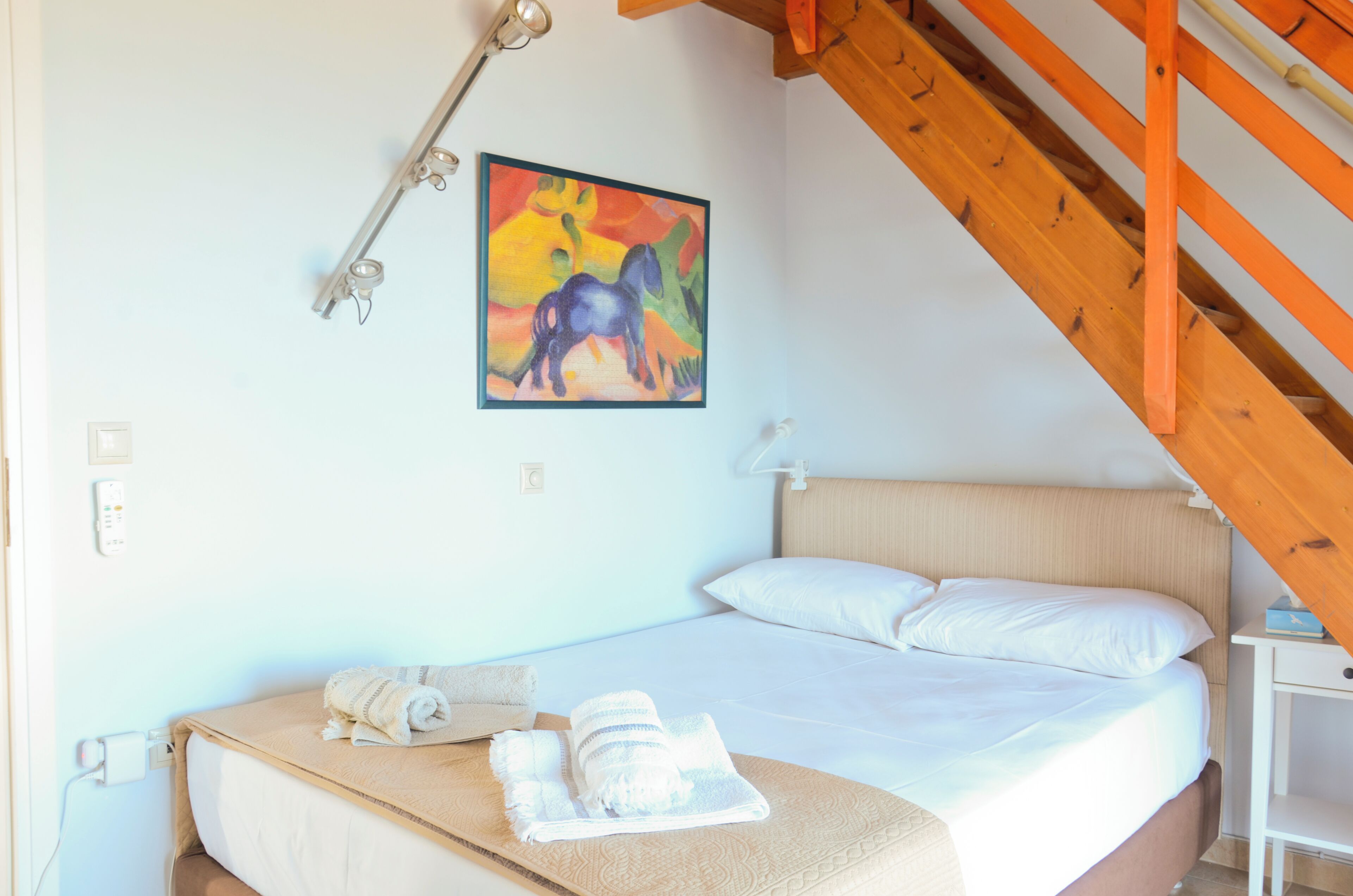 Une chambre à coucher avec un lit, un tableau, un plafond en bois et une table de chevet.