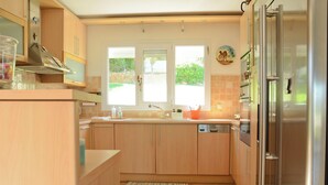 Una cocina moderna con armarios de madera, un refrigerador de acero inoxidable y una ventana con vistas a un jardín.