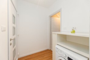 A laundry room with a washing machine, a shelf with a bottle, and a door with a handle. - Torino Regio Parco | Mantova House 2  (Torino)