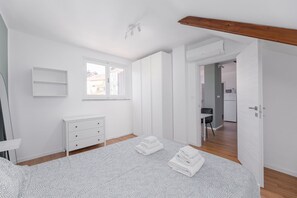 A bedroom with a bed, a dresser, a window, and a door leading to a kitchenette. - Torino Regio Parco | Mantova House 2  (Torino)