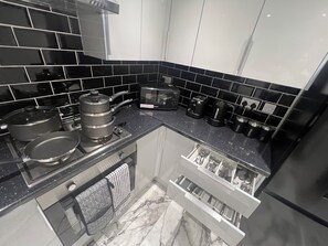 A kitchen with black tiled backsplash, stainless steel appliances, and a marble countertop. - Superb 4 bedrooms with 2 receptions (Linford)