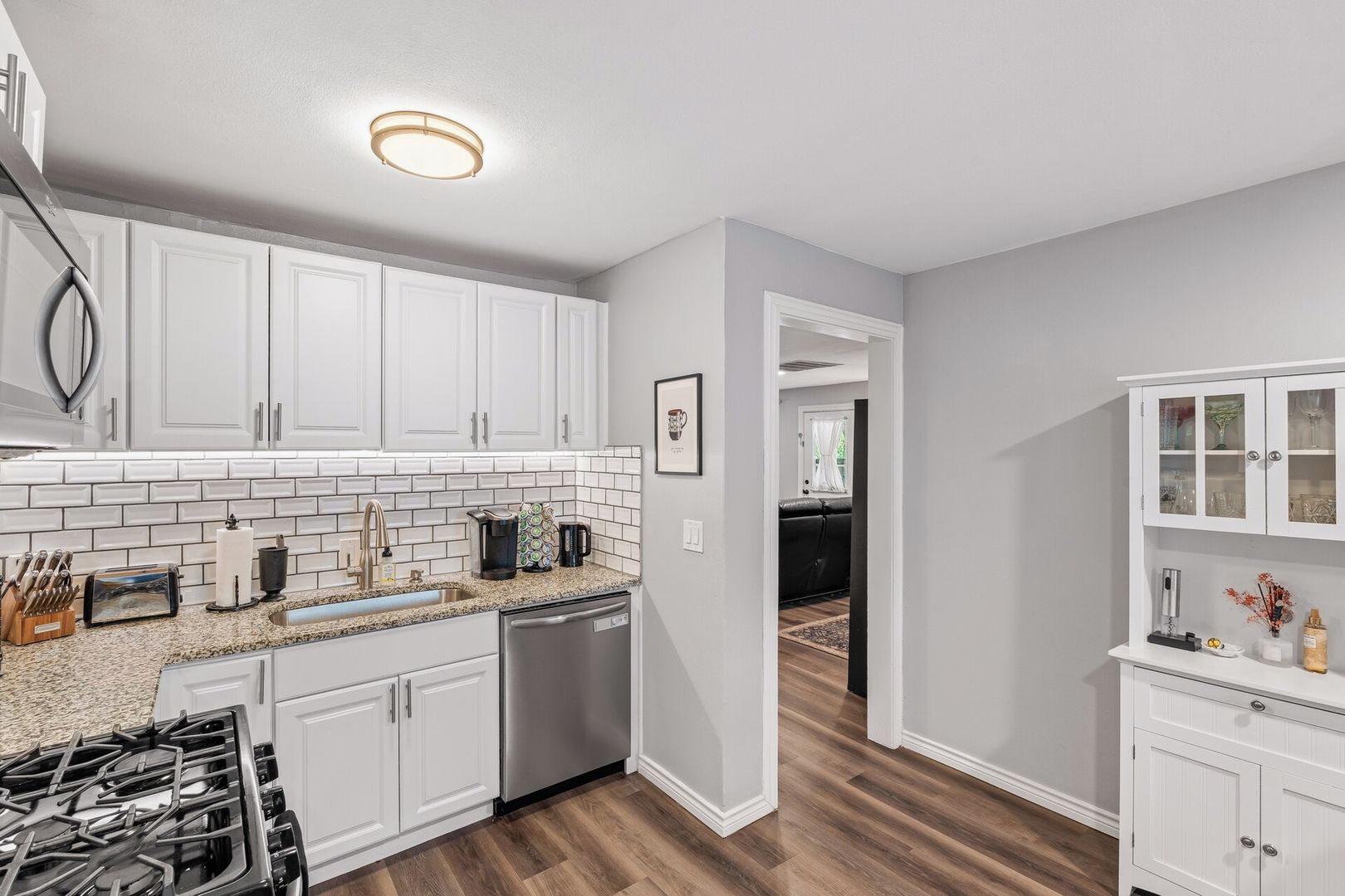 A modern kitchen with white cabinets, a stainless steel dishwasher, and a granite countertop.