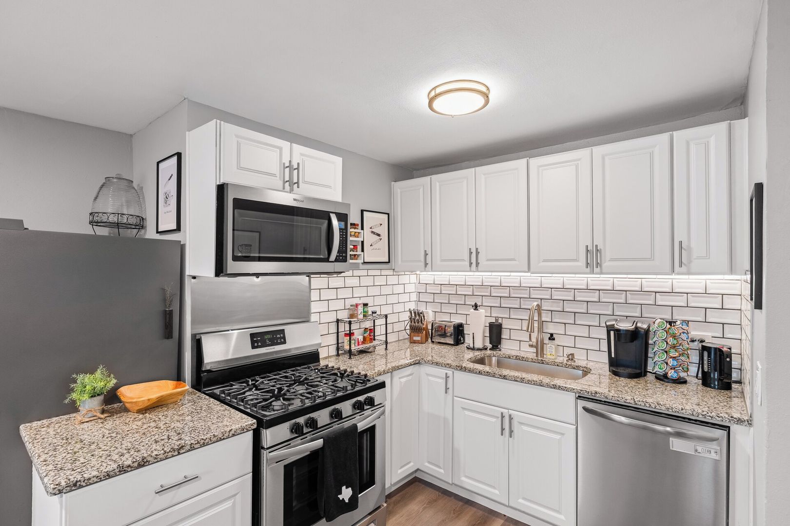 A modern kitchen with white cabinetry, a stainless steel range, a microwave, and a dishwasher.