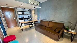 Ein modernes Wohnzimmer mit einer Couch, einem Esstisch und einer Küchenzeile im Hintergrund.