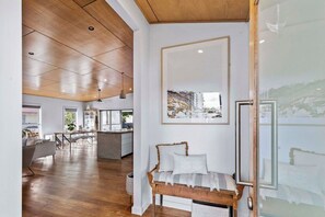 A spacious living area with a wooden ceiling, a dining table, and a bench with cushions.