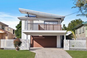 A modern two-story house with a garage, stone walls, and a white picket fence.