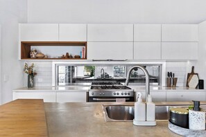A modern kitchen with white cabinets, stainless steel appliances, and a wooden countertop.