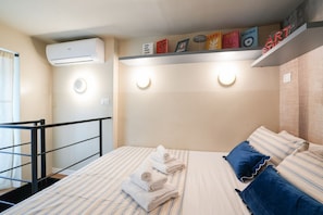Ein Hotelzimmer mit Bett, Handtüchern, einem Regal mit Dekoration und einer Klimaanlage.