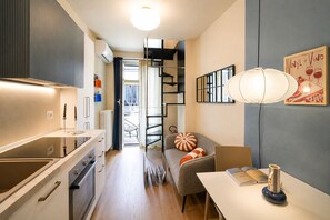 Eine moderne Küche mit Backofen, ein Essbereich mit Tisch und Stühlen sowie eine Treppe zu einem Balkon im Freien.