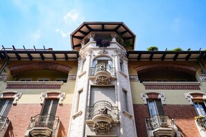 Ein Gebäude mit einem zentralen Turm, Balkonen und einem Ziegeldach.