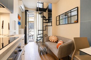 A modern living space with a kitchen, a sofa with decorative pillows, a dining area, and a staircase. - Cit Turin | Casetta Sogni (Torino)