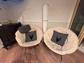 Two beige bean bag chairs with metal frames and black cushions featuring a deer silhouette, positioned against a white wall with a wooden floor. - Boutique Family Alpine Retreat - Skiing, Parking (Chamonix-Mont-Blanc)