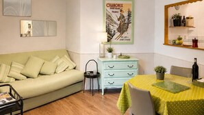 Un espace de vie compact comprenant un canapé, une table à manger avec des chaises, une petite commode et un miroir.
